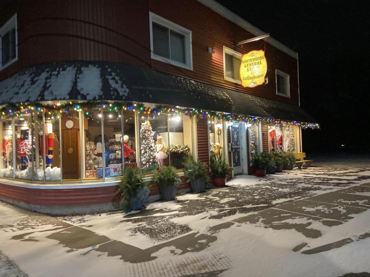 Cozy store with festive lights, snow-covered sidewalk at night.
