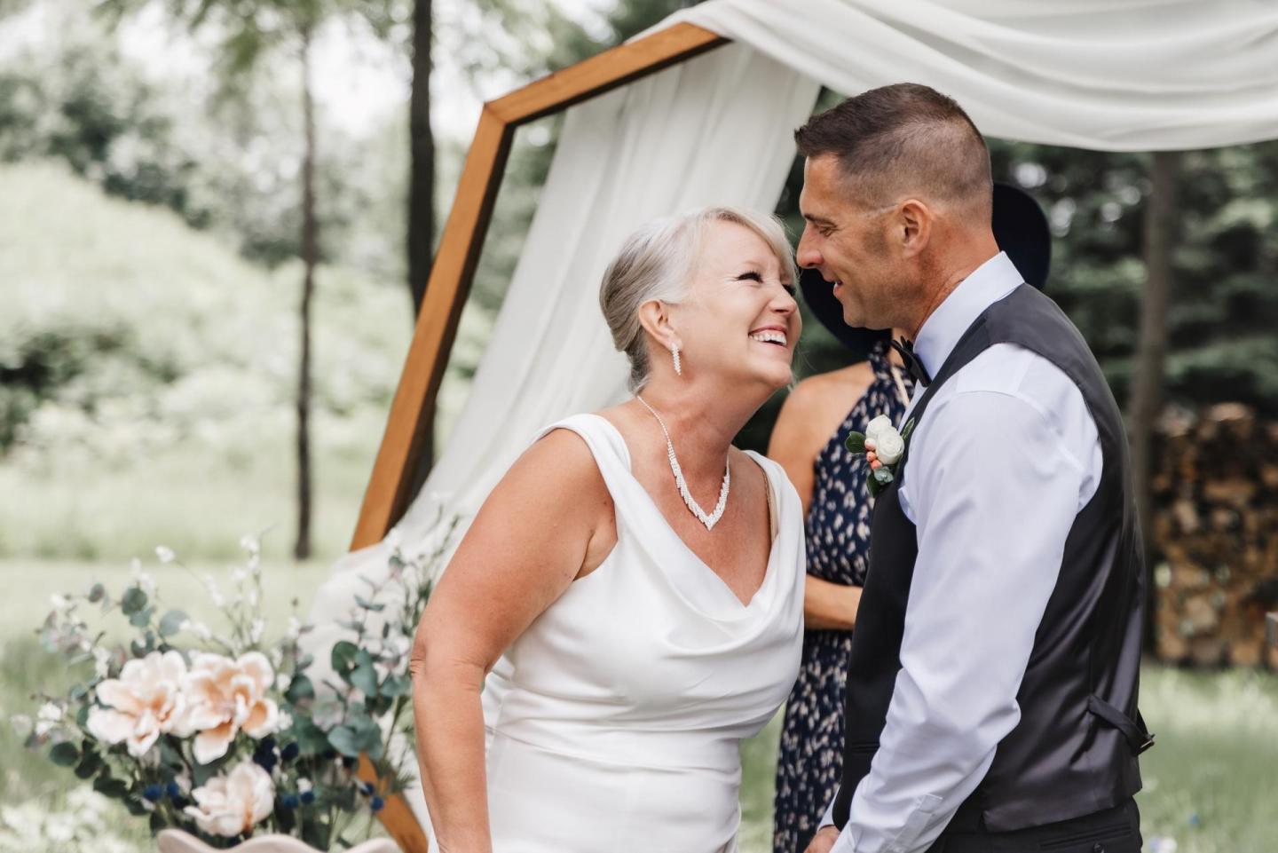 Couple smiling at each other at an outdoor wedding ceremony.