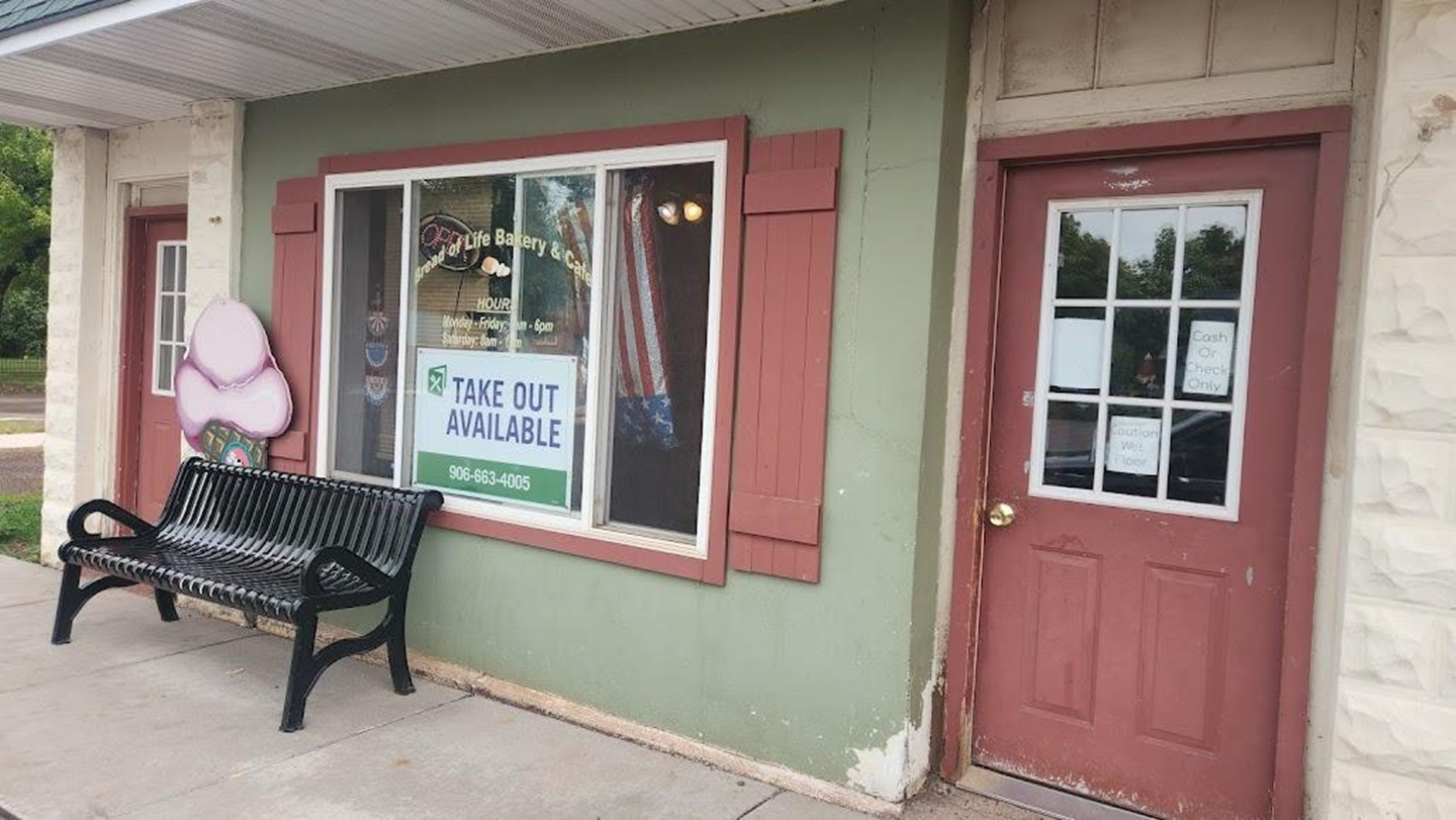 Storefront with a red door, window with a poster, and a black bench outside.