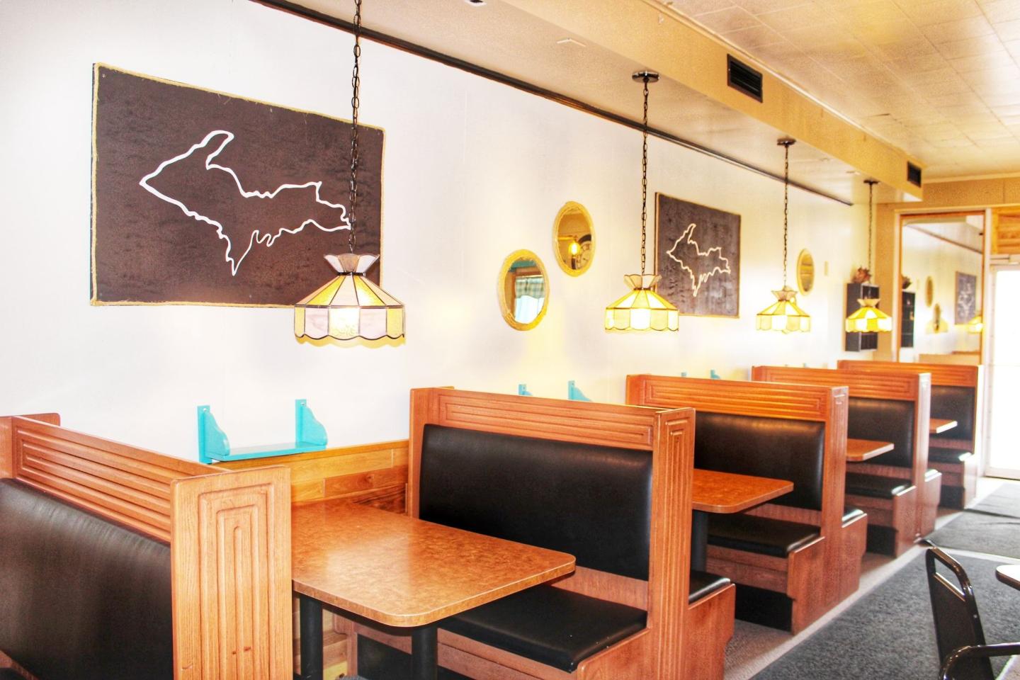 Café with wooden booths, pendant lights, and map wall art.