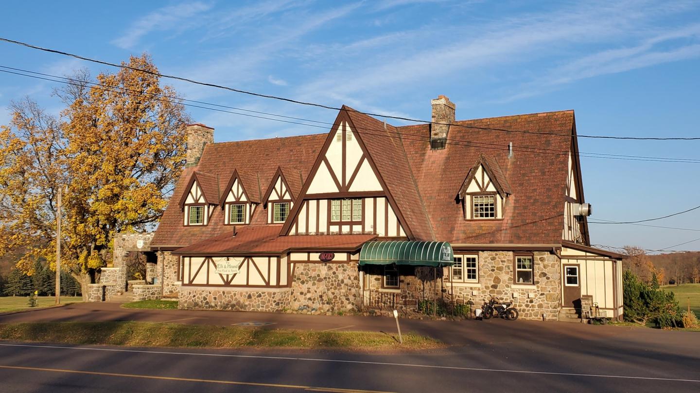Tudor-style house with stone facade, under a clear blue sky.