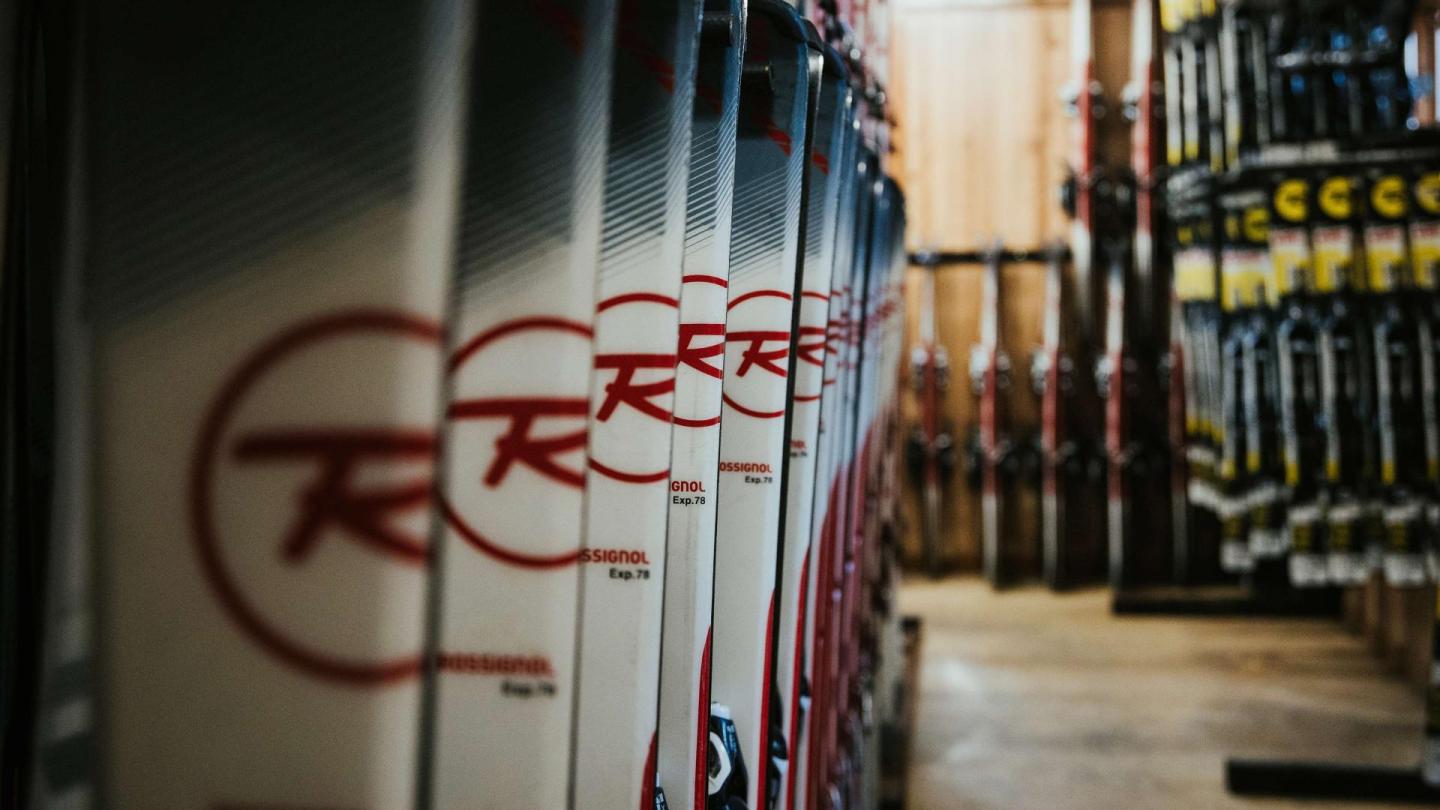 Rows of skis with red logos in a dimly-lit storage area.