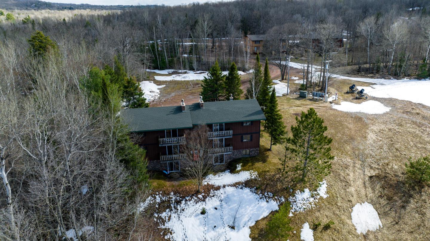 Lodge surrounded by trees and melting snow in early spring landscape.