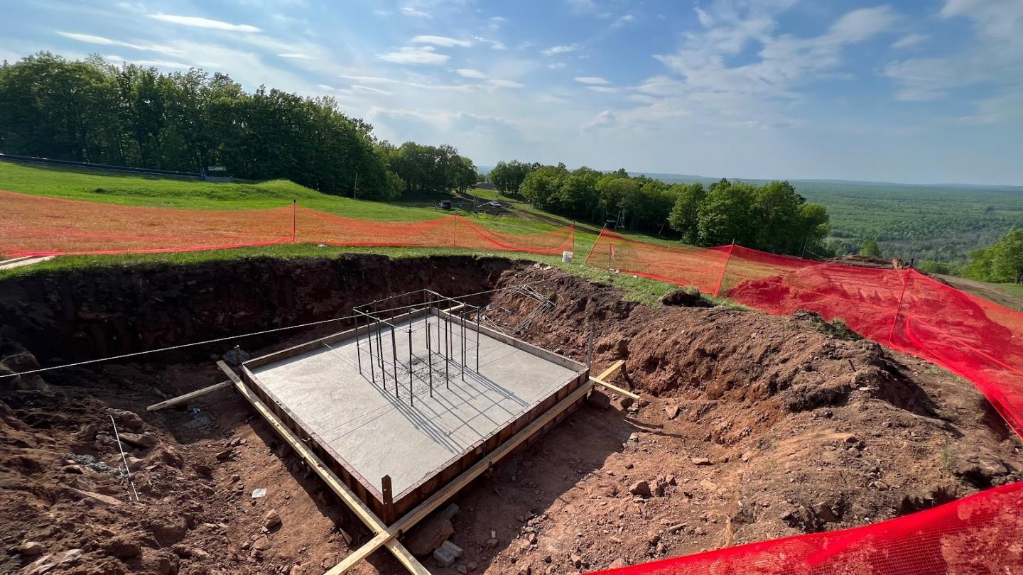 Construction site with foundation and rebar under a blue sky.