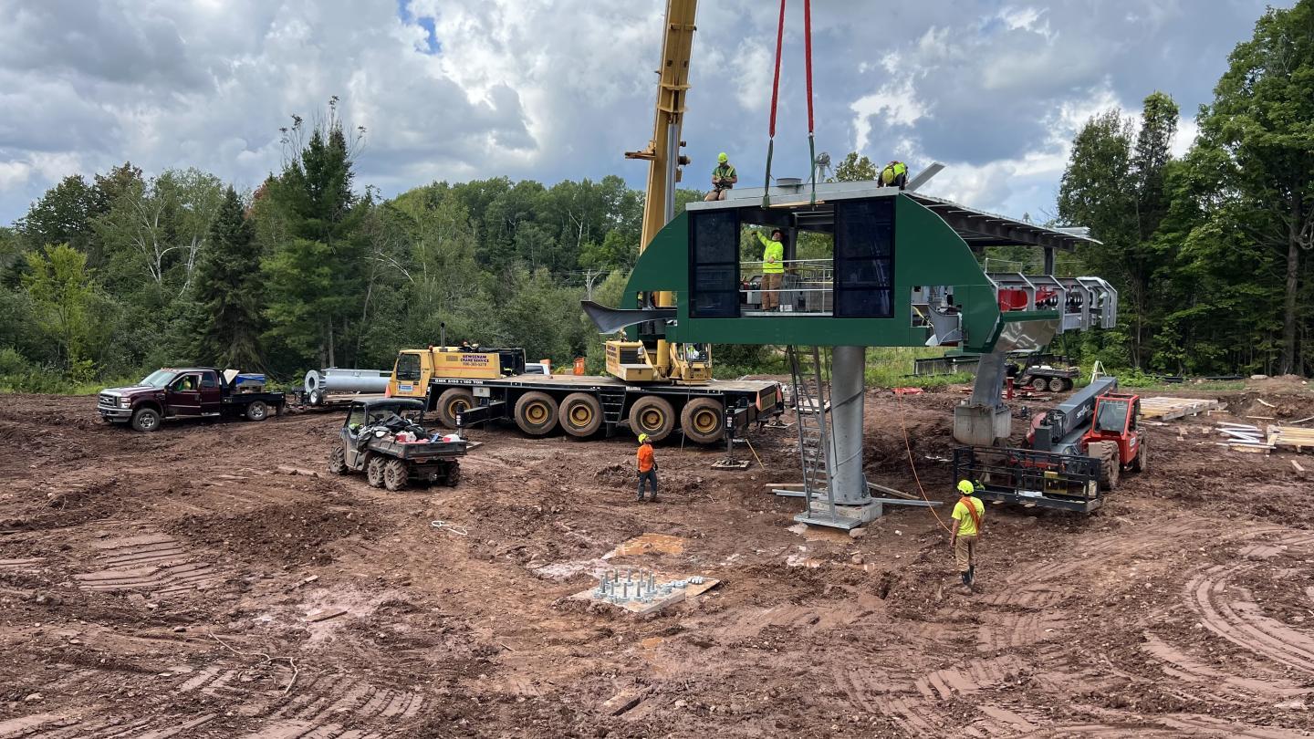 Construction site with heavy machinery and workers assembling a metal structure.