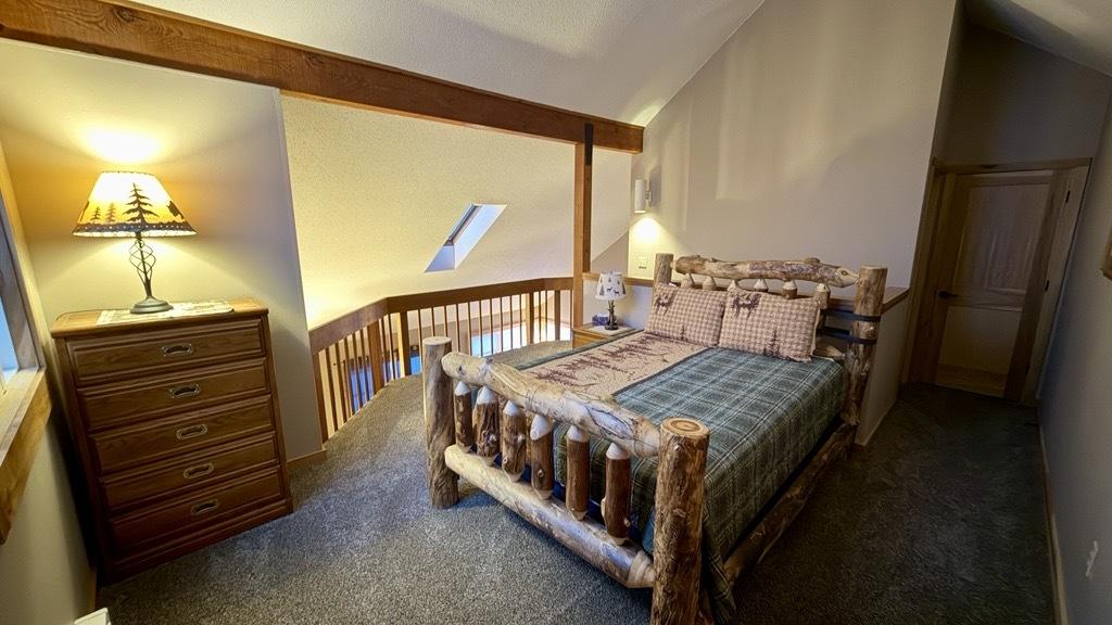 Cozy loft bedroom with wooden bed, dresser, and warm lighting.