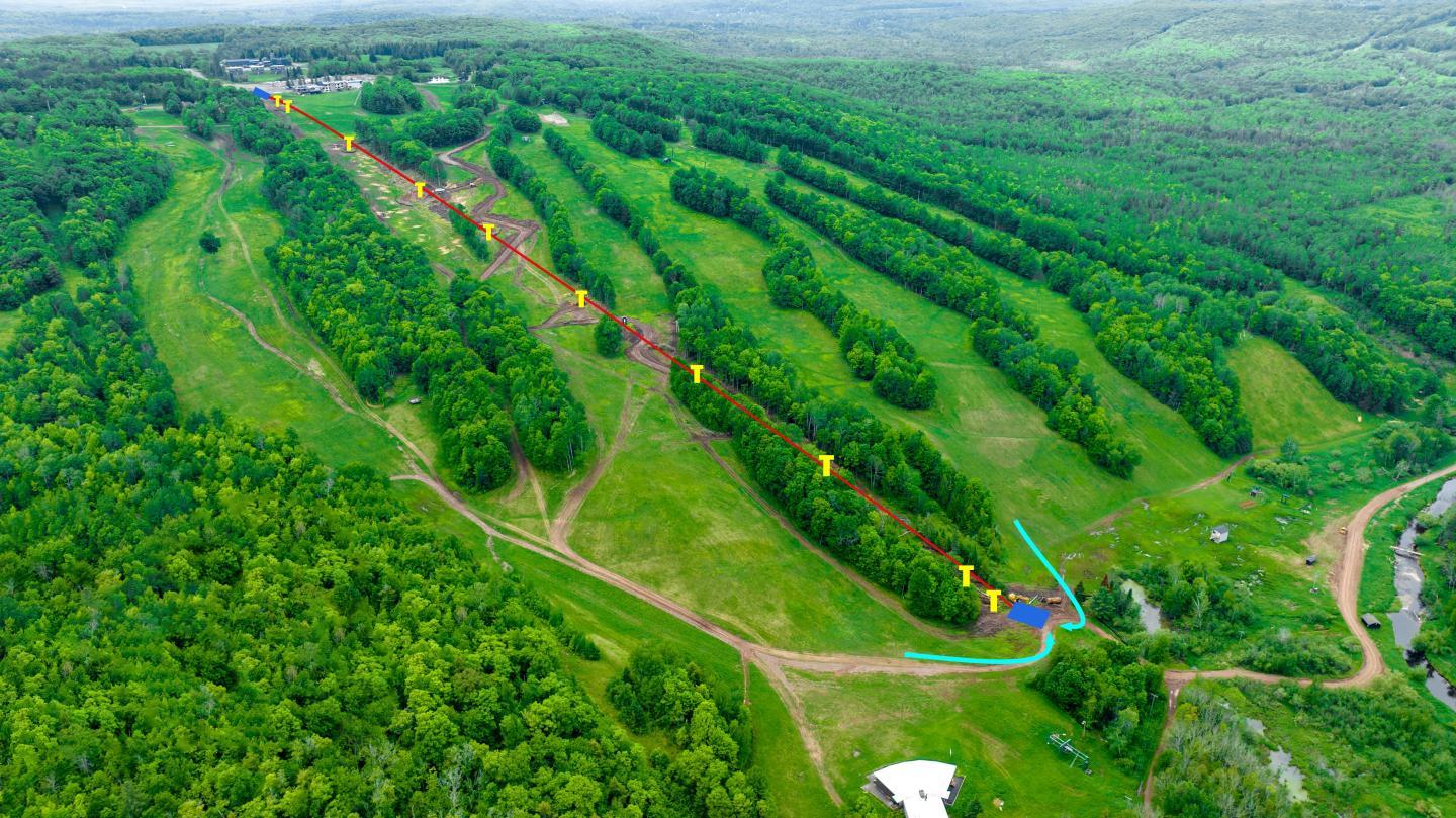 Aerial view of a lush green landscape with ski trails outlined.
