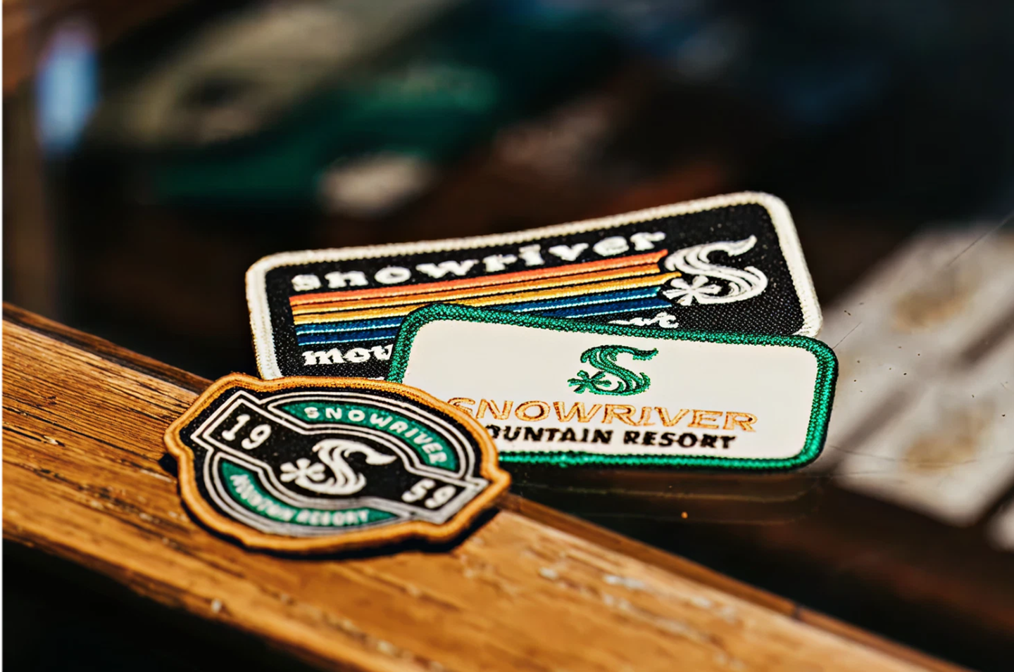 Patches of Snowriver Mountain Resort on a wooden surface.