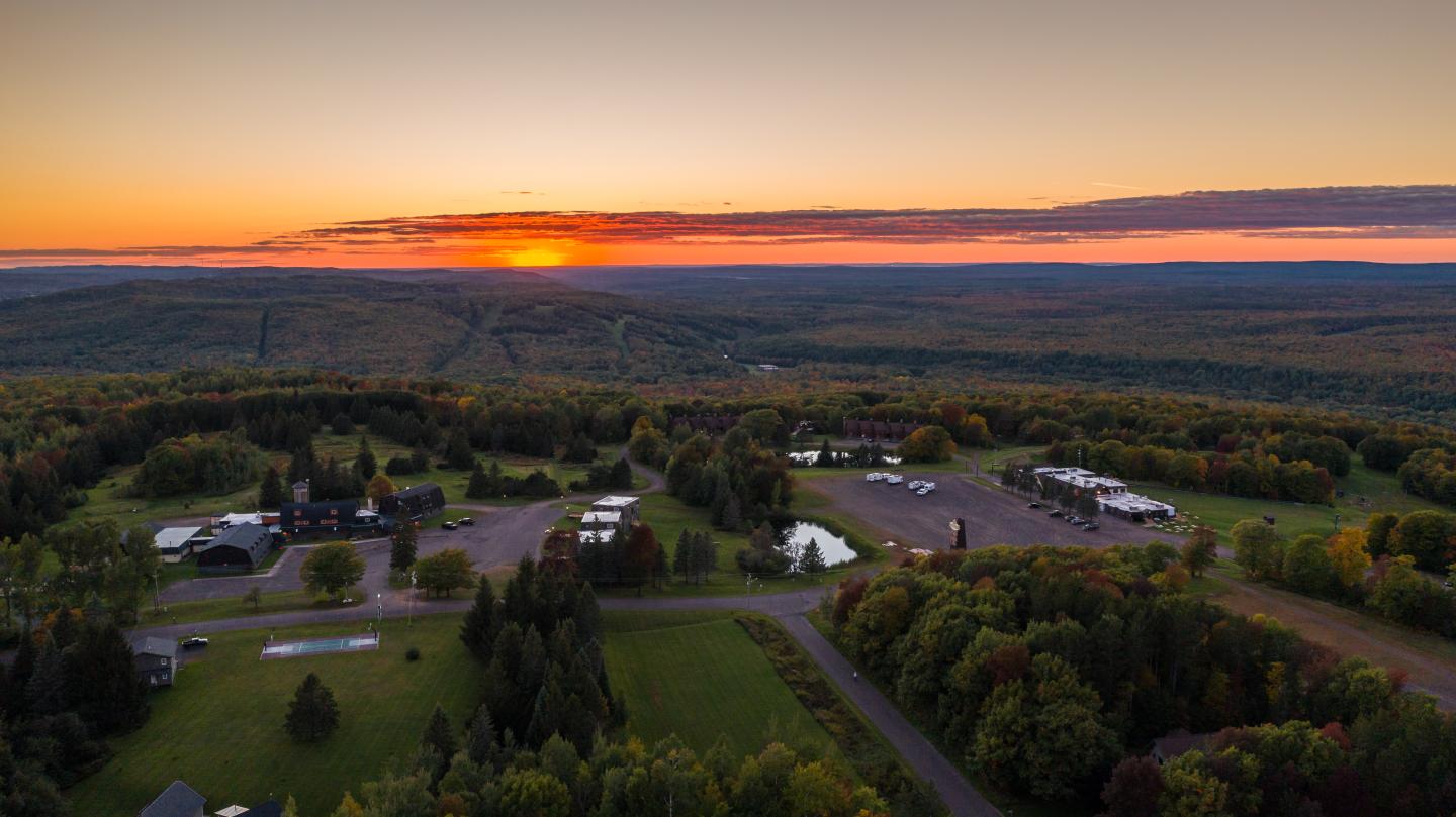 Sunset over a rural landscape with scattered buildings and lush greenery.