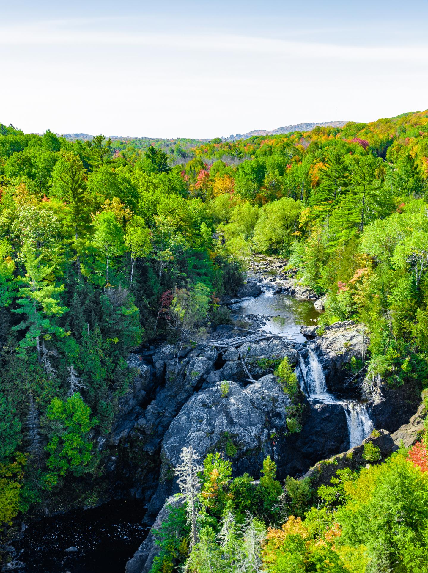 Waterfall cascading through a lush forest with autumn colors.
