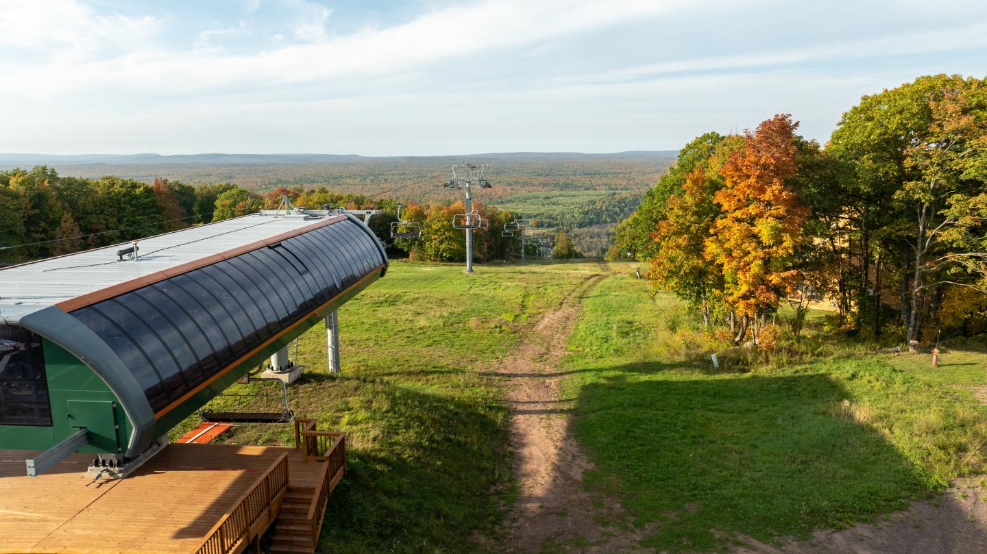 Ski lift station overlooking a lush green and colorful autumn landscape.