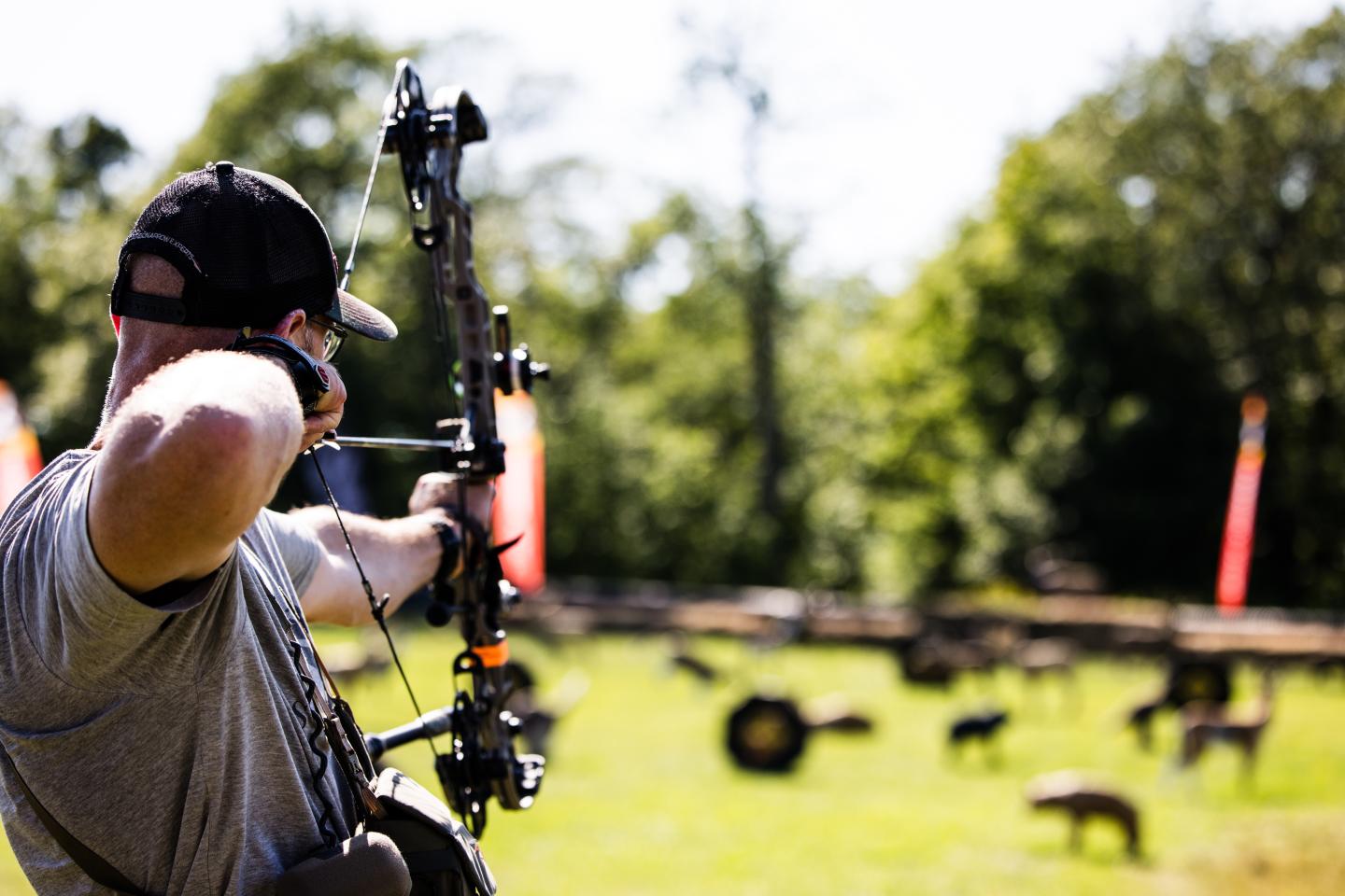 Archer aiming at targets in a sunlit grassy field.