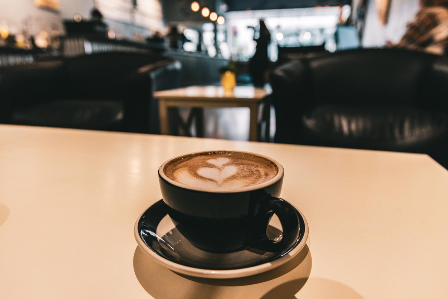 Coffee cup with latte art on a cafe table, cozy ambiance.