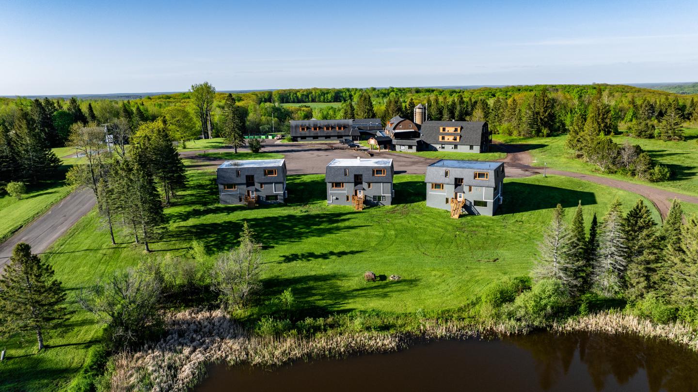 Aerial view of modern buildings on lush green landscape near a pond.