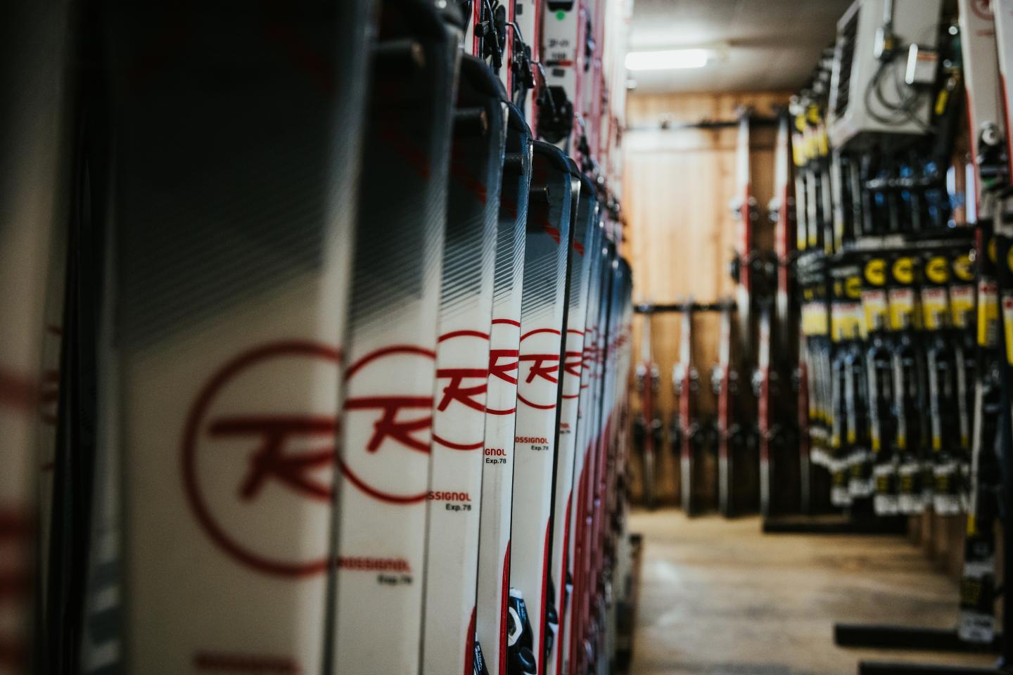 Skis lined up in storage room, dim lighting.