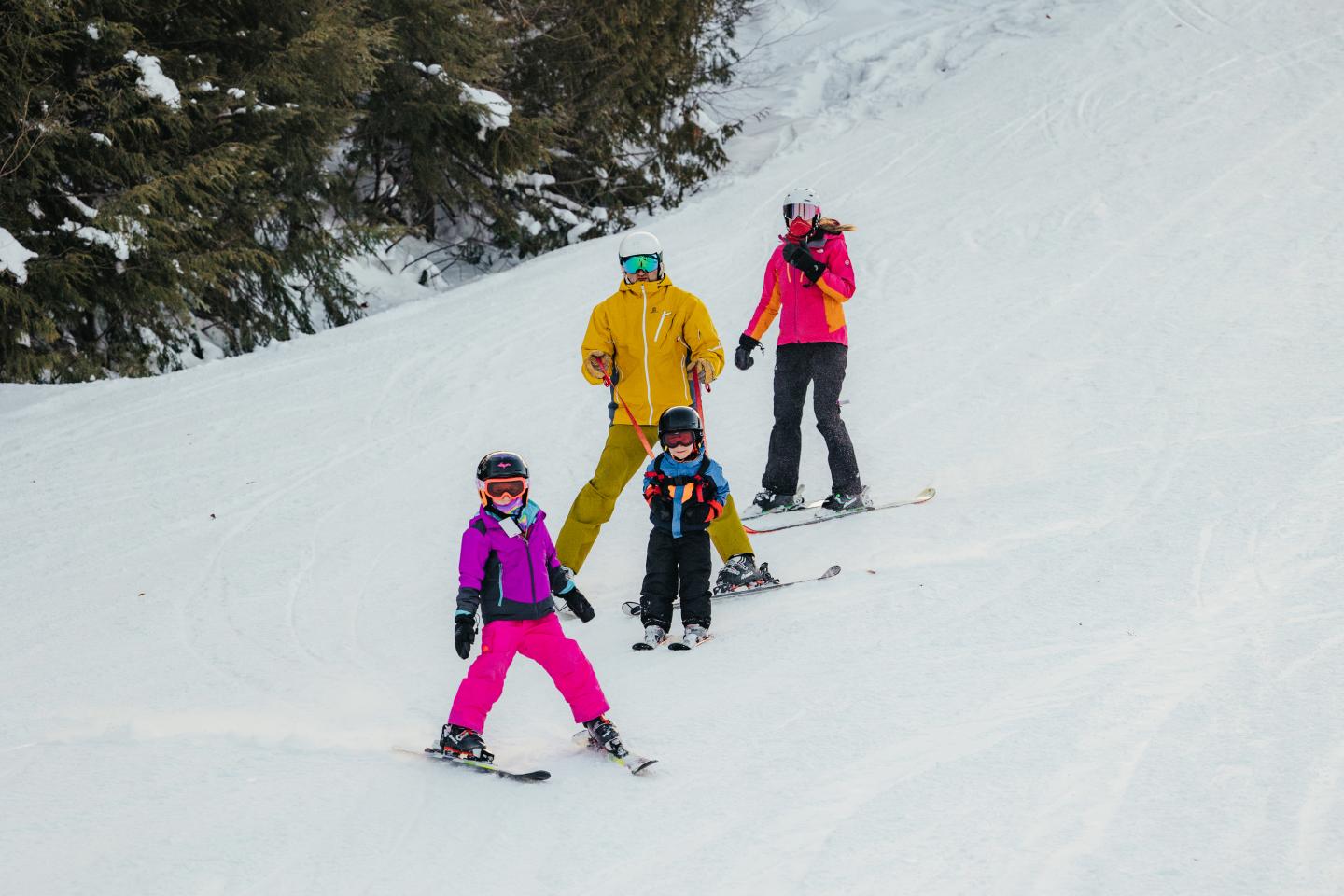 Four people skiing down a snowy slope in colorful outfits.