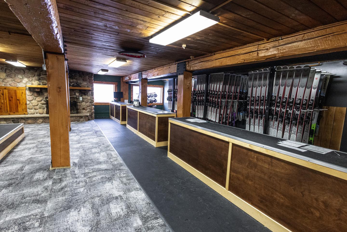 Rustic wooden interior with a counter and ski racks on the walls.