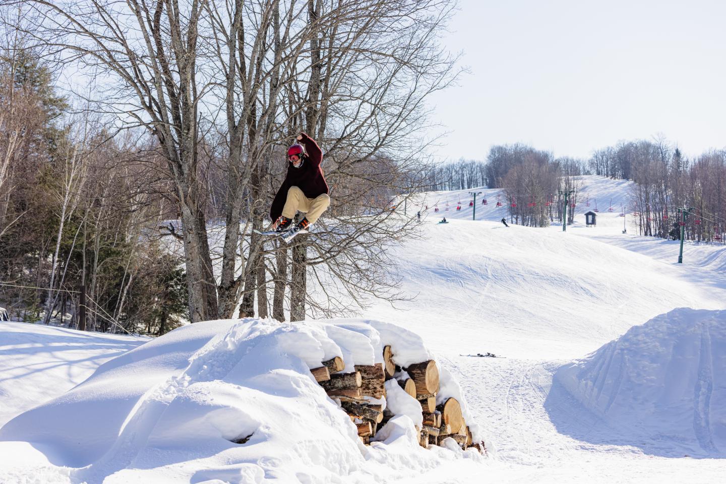 Snowboarder jumping off a snowy ramp against a clear sky.