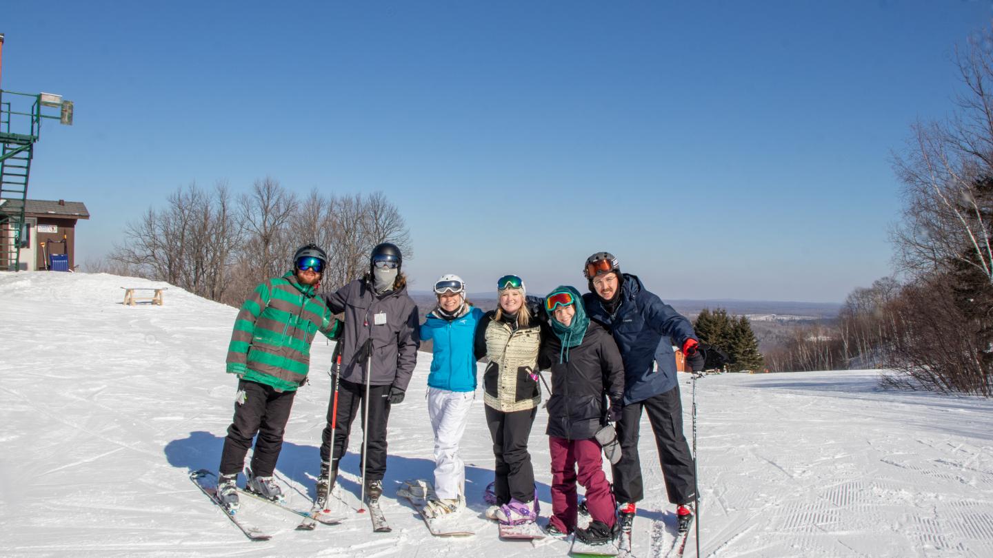 Group of skiers on a snowy slope under a clear blue sky.