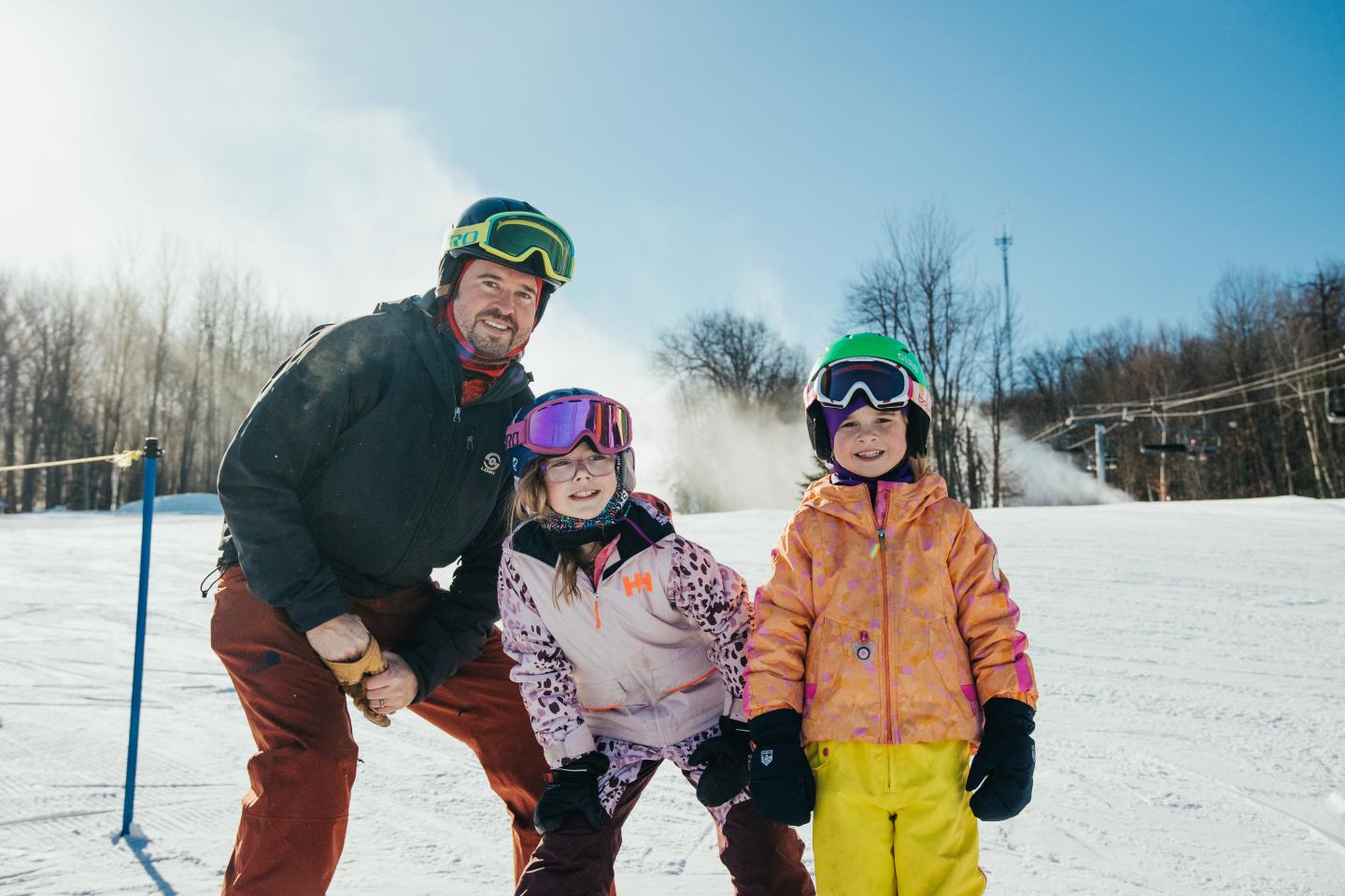 Family in colorful winter clothes skiing on a snowy slope