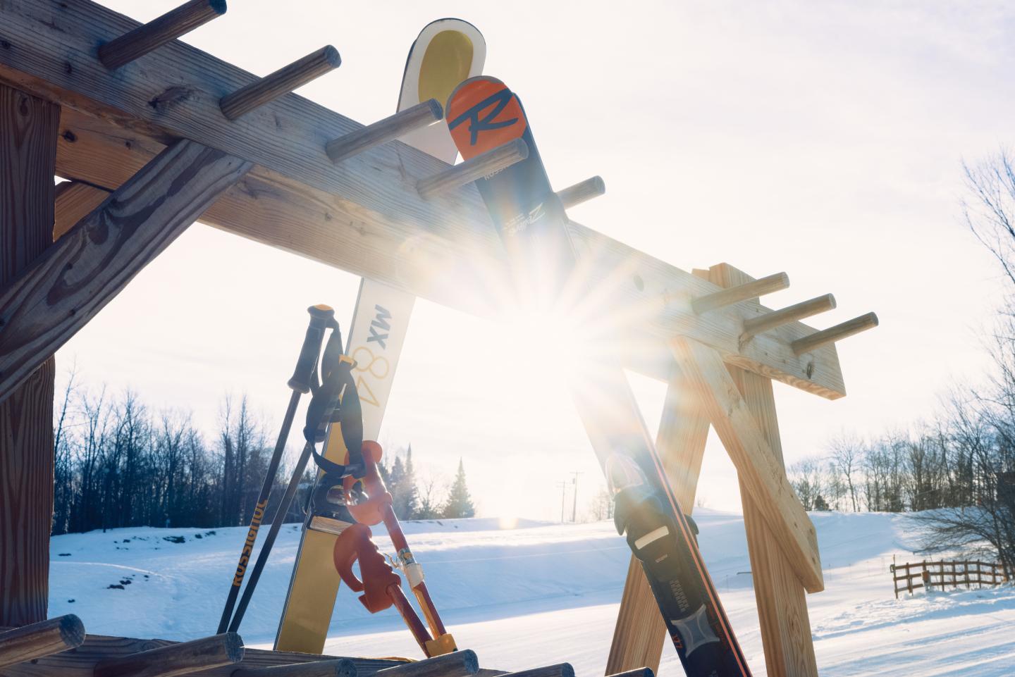 Sun shining through a wooden ski lift structure over snowy ground