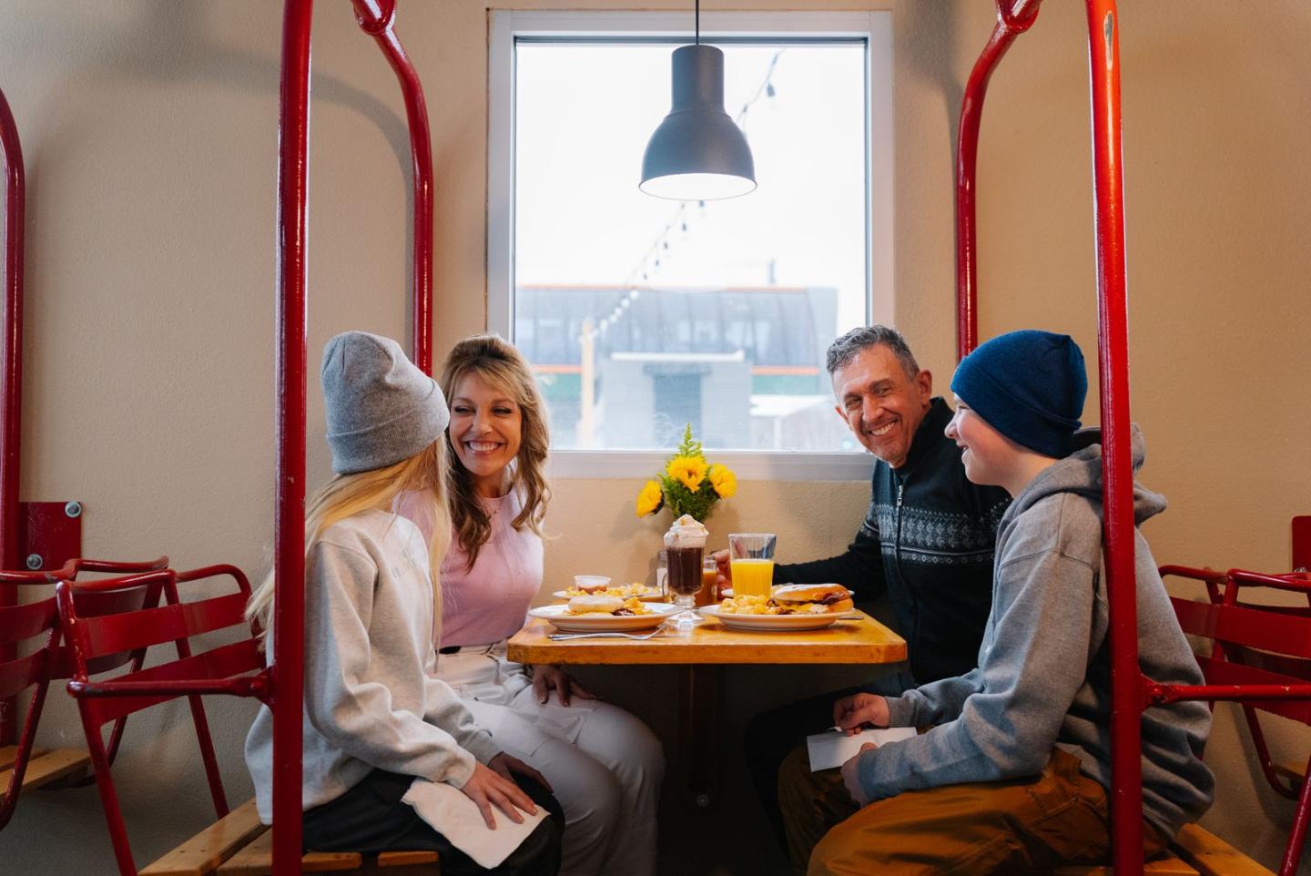 A family dining and smiling at a café table by a window.
